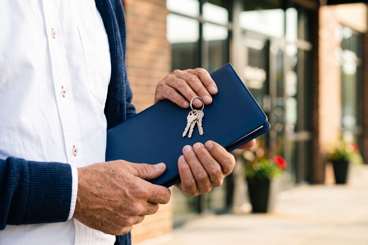 Business owner holding a navy folder and new shop keys outside a storefront